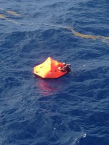A Coast Guard rescue swimmer grabs hold of a life raft Thursday about 32 miles south of St. Croix. The helicopter crew rescued two people who had abandoned their sinking vessel. (Coast Guard photo)