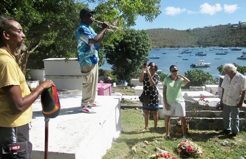 Emmanuel Boyd, a security guard at nearby Gallows Point Resort, plays his trumpet Monday for an informal ceremony honoring those who have served and fallen in the U.S. military and are resting in the Cruz Bay cemetery. (Judi Shimel photo)