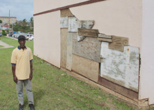 Thomasville resident Simon Rawlins, Sr. stands next to his hurricane-damaged wall, which is patched together with salvaged plywood.