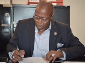 Senate President Myron Jackson signs documents finalizing the purchase of the new St. Croix legislative building.