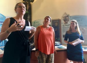 Meaghan Enright explains the Resilient Housing Initiative while Heidi Arnold and Celia Kalousek listen.