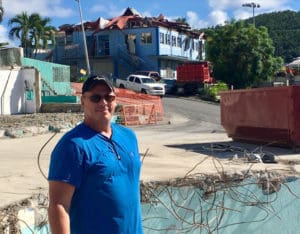 David Olson stands in Lumberyard Complex. The damaged Sprauve School building is in the background.