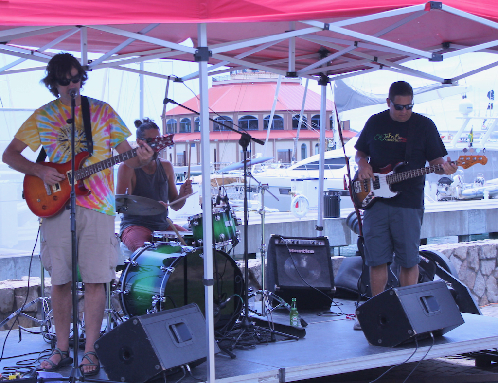 The band Cat 3, consisting of a drummer, bass guitar and singer/lead guitar, entertained festival goers with music from a central stage in Yacht Haven Grande.