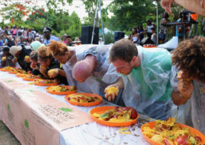 Single-handed mango eating was the rule for the adults and they attempted to get through the large plate of mangos. (Source photo by Linda Morland)