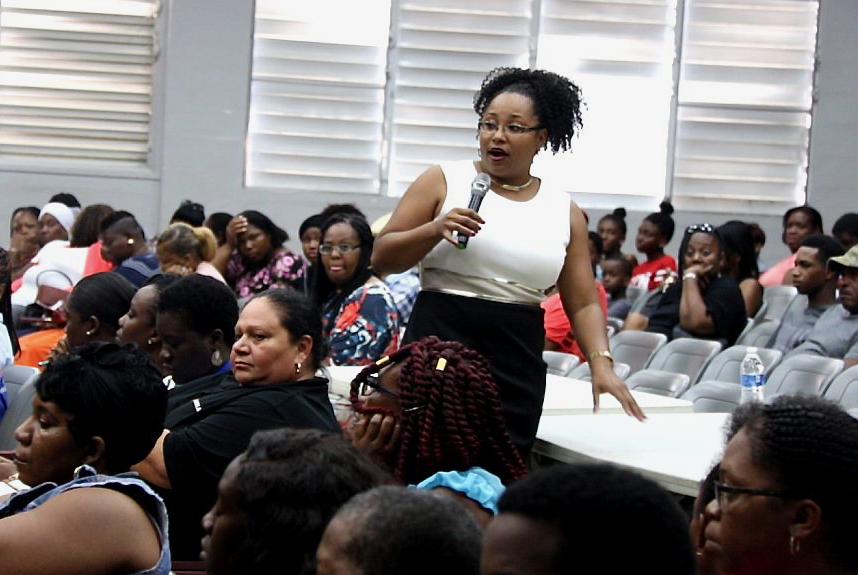 At a packed community meeting Thursday, Education Commissioner Racquel Berry-Benjamin details the department’s plans to move three schools. (Source photo by James Gardner)