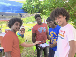 Kitty Edwards of DPNR assists CAHS students Khaleel Smith, Elijah Rabatt Rae’Heim White, and Reuben Martin with trash collection weigh-in at Brewers Bay. (Source photo by Teddi Davis)