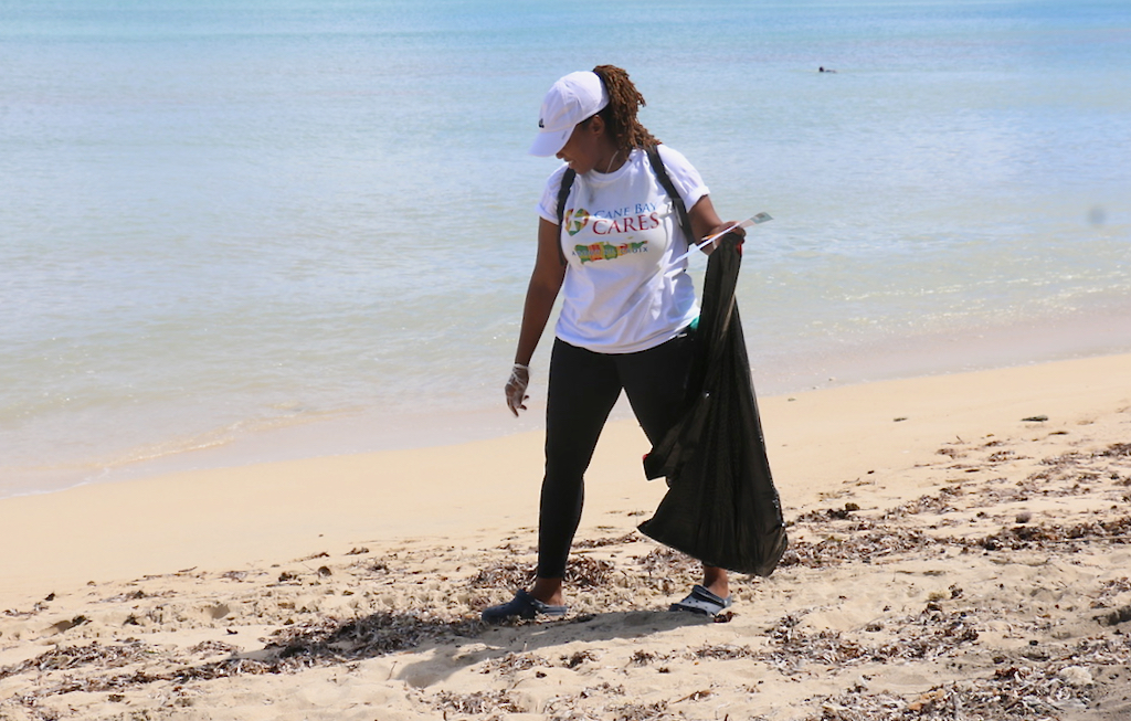 Precious Laurent, one of the team from Cane Bay Cares, walks the sand looking closely for small, sharp objects. (Source photo by Linda Morland)