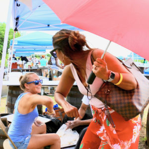 USVI first lady Yolanda Bryan bumps elbows with Michelle Mehalick, whose hands are full of dough, at the Un Amore booth at Bush Cook Chef Cook. (Source photo by Linda Morland)