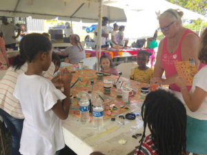 Cindy Salomone shows children how to make bee floats. (Source photo by Susan Ellis)
