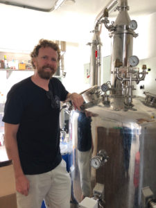 John Brugos poses by the firm's new still at Virgin Islands Craft Distillers in Crown Bay. (Source photo by Teddi Davis)