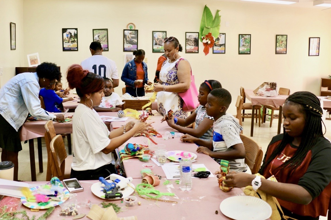 Grace King, 4-H Ambassador (center) helps as children gather at her table to work on ornaments using bright madras fabric. (Source photo by Linda Morland)
