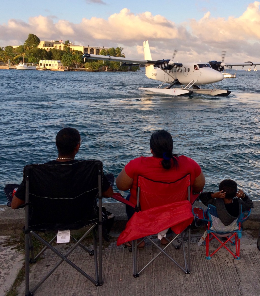 A Seaborne plane maneuvers in the harbor as a well-situation family watches. (Source photo by Don Buchanan)