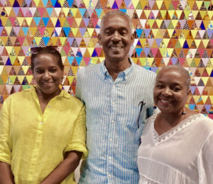 Avelino Samuel, center, and Karen Samuel, right, pose with their sister Coreen in front of a quilt made by Karen. (Photo submitted by the Samuel family)