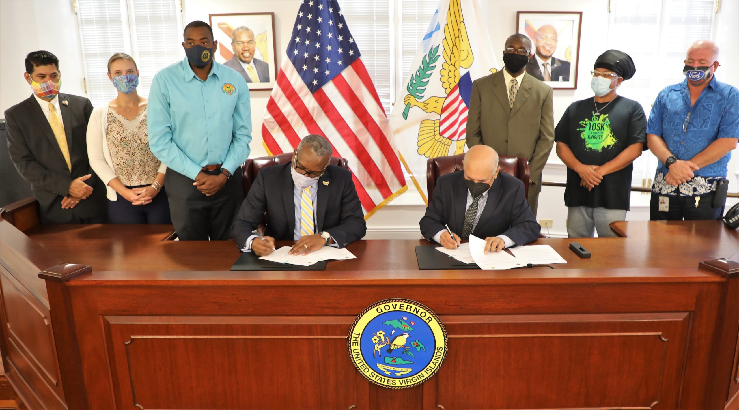 Gov. Albert Bryan Jr. and Jehangir Zakaria. vice president of Engineering/Energy for Renaissance Group LLLP, sign the agreement for a 2.5- acre donation of land to be used for the construction of a drag racing facility on St. Croix while members of the Bryan-Roach administration and the Caribbean Drag Racing Association look on. (Photo by Government House)