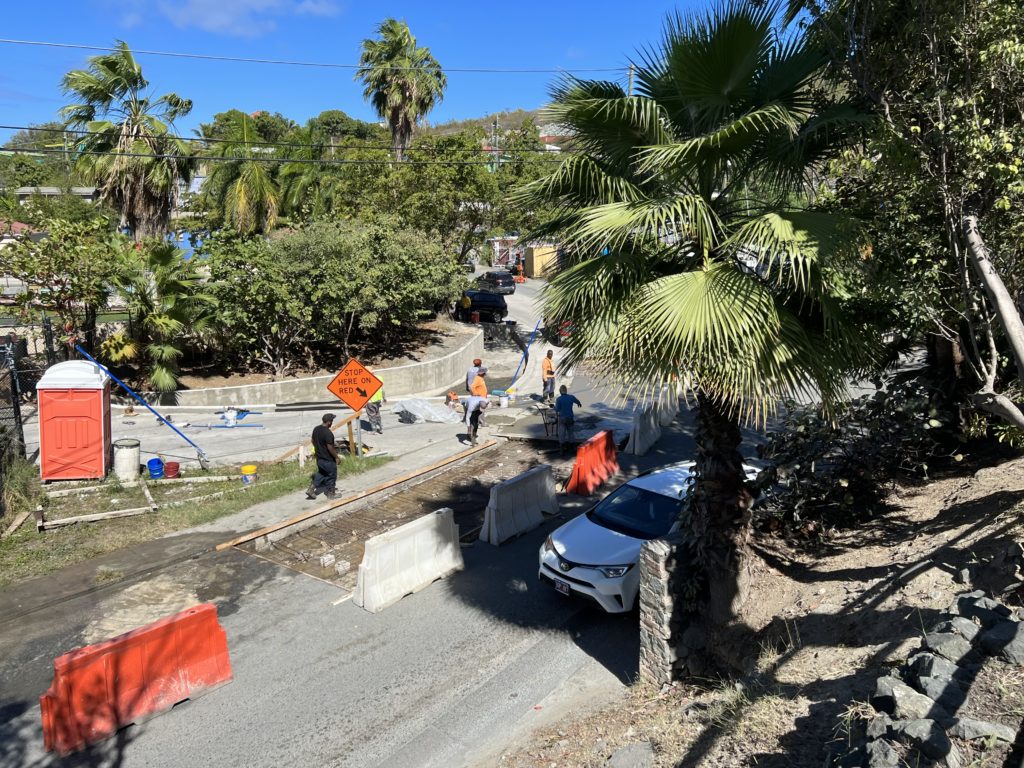 Work continues along the road in front of the Marketplace. As a car exits the parking lot onto the one-lane street below, at least a dozen more were waiting patiently behind to do the same. (Source photo by Amy H. Roberts)