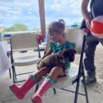 Alice Bencosme, 2 years old, holds puppy at the St. Croix Welfare Center booth at the 2022 Agricultural Fair in St. Croix