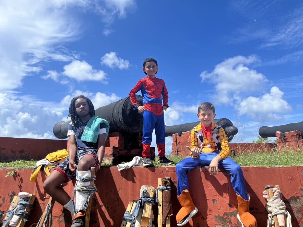 Children strap up for mocko jumbie stilt walking. (Source Photo by Diana Dias)