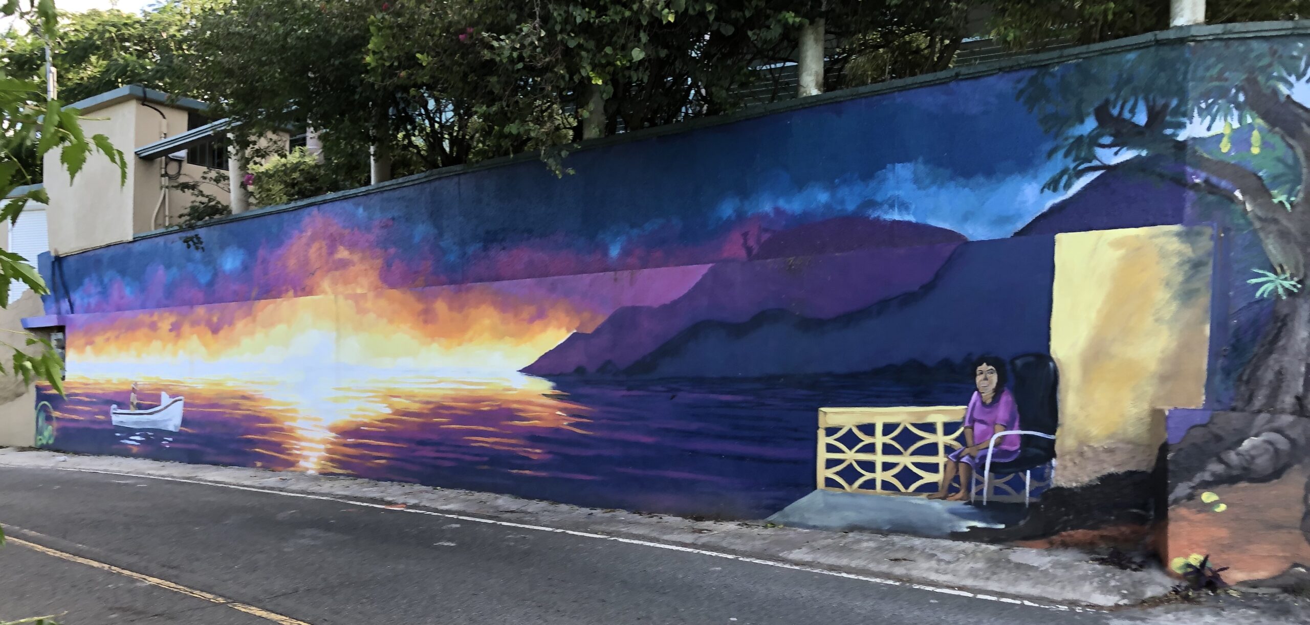 A mural by Megan Lyn encompasses the two concrete walls that surround the home of Rita Greaux and Paul Berry at the foot of Barrett Hill Road in Hull Bay. The work was commissioned as a tribute to both sides of the family, reflecting the fishing and the farming that was, and remains, the backbone of the community. (Source photo by Sian Cobb)