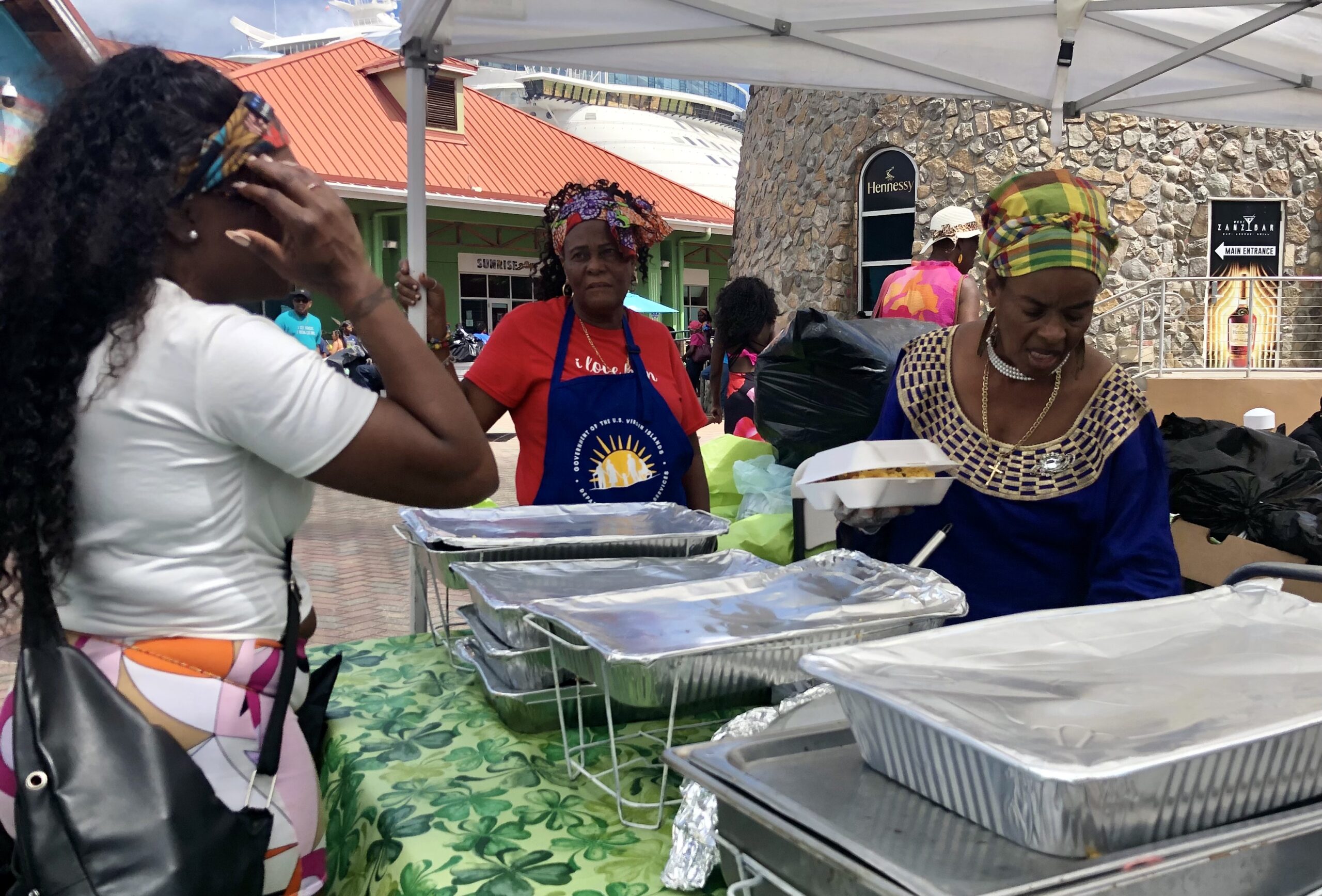Theresa Davis (front, right) and Aurora Johnson (center) pack an order for a Food Fair patron near the Wonder of the Seas. (Source photo by Judi Shimel)