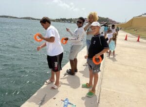 Angie Estein brought three boys, Mathew Simmons, age 10, Jabmel Navarro, age 11 and Angel Valesquez, age 12, to participate. “They like to fish and know not to eat them or kill the fish,” she said. (Source photo by Susan Ellis)