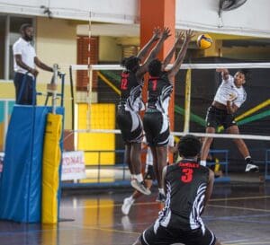 1. Armani Anderson, ISV, spikes the ball past two Trinidad & Tobago blockers in his semi-final match at the CAZOVA U19 Volleyball Championships. (Photo by Sean Morrison)