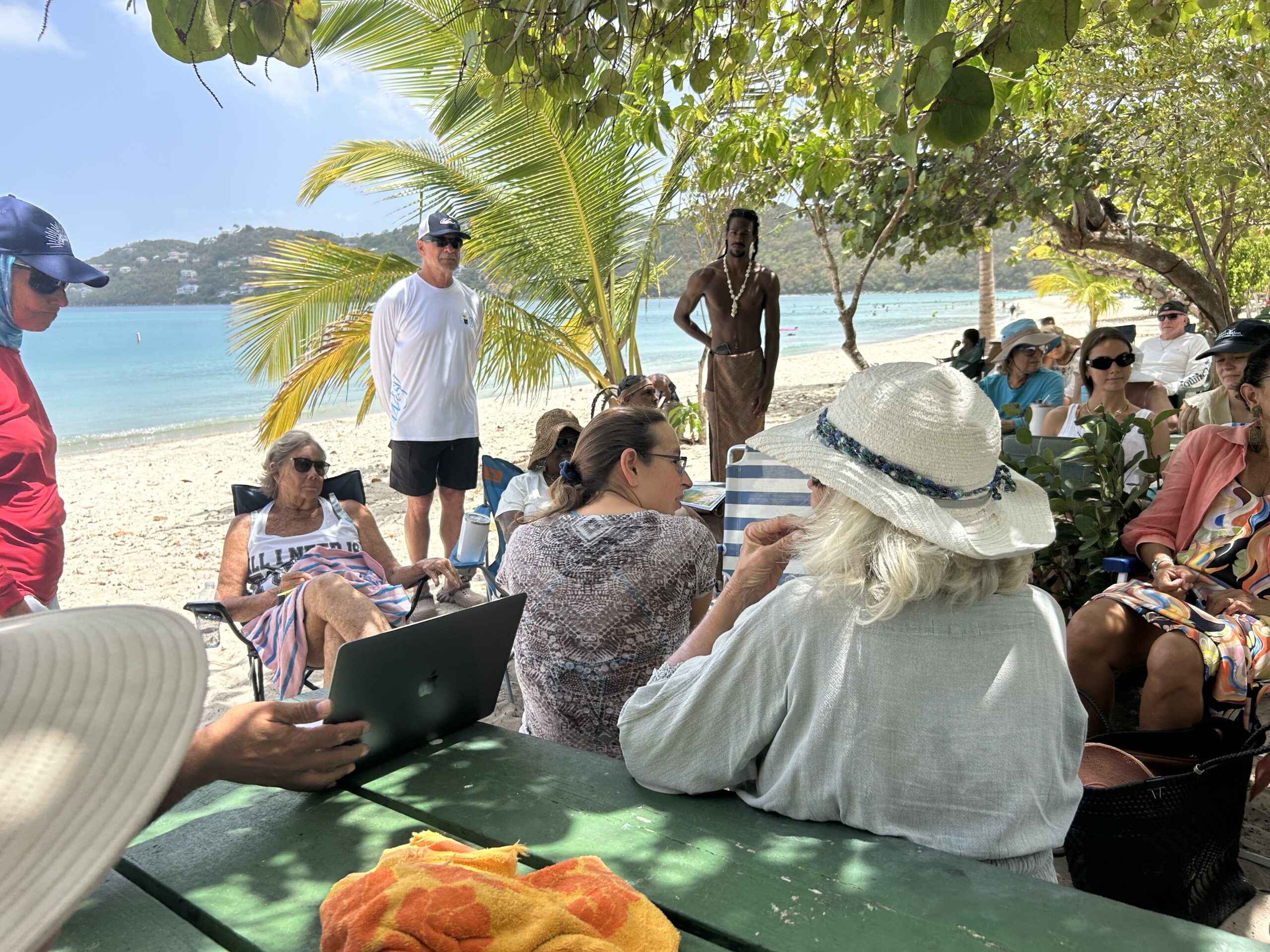 Sara Smollett, seated center, leads the Friends of Fairchild at Magens Bay community meeting Saturday, under the trees at the beach. (Source photo by Siân Cobb) 
